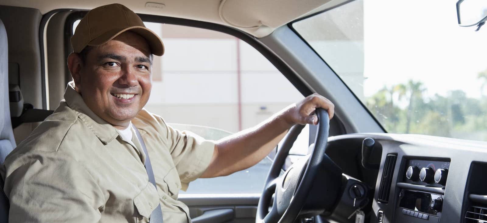 Truck driver smiling while sitting inside truck